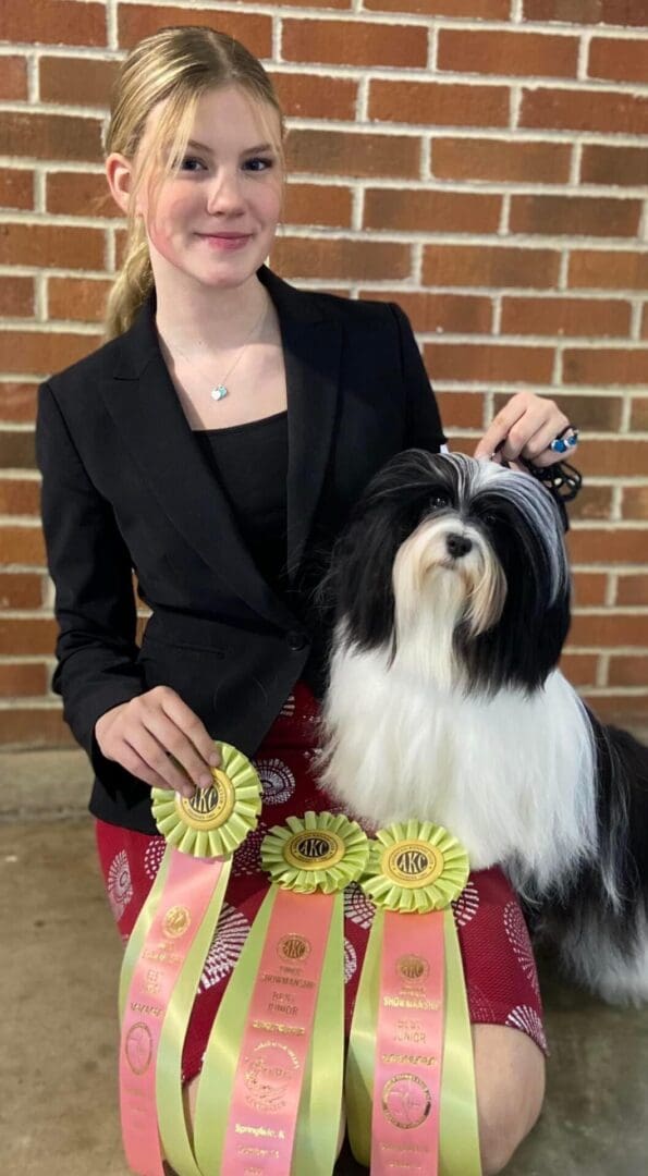 A woman posing with her shih tzu and ribbons.