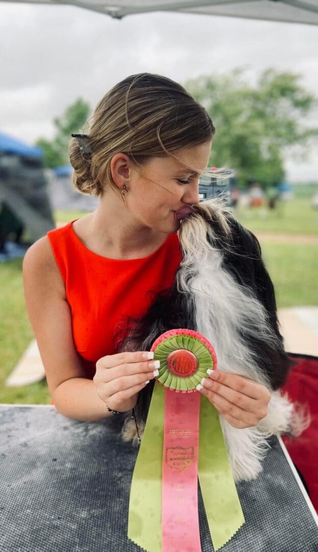 A woman affectionately kisses a Havanese puppy at a dog show.